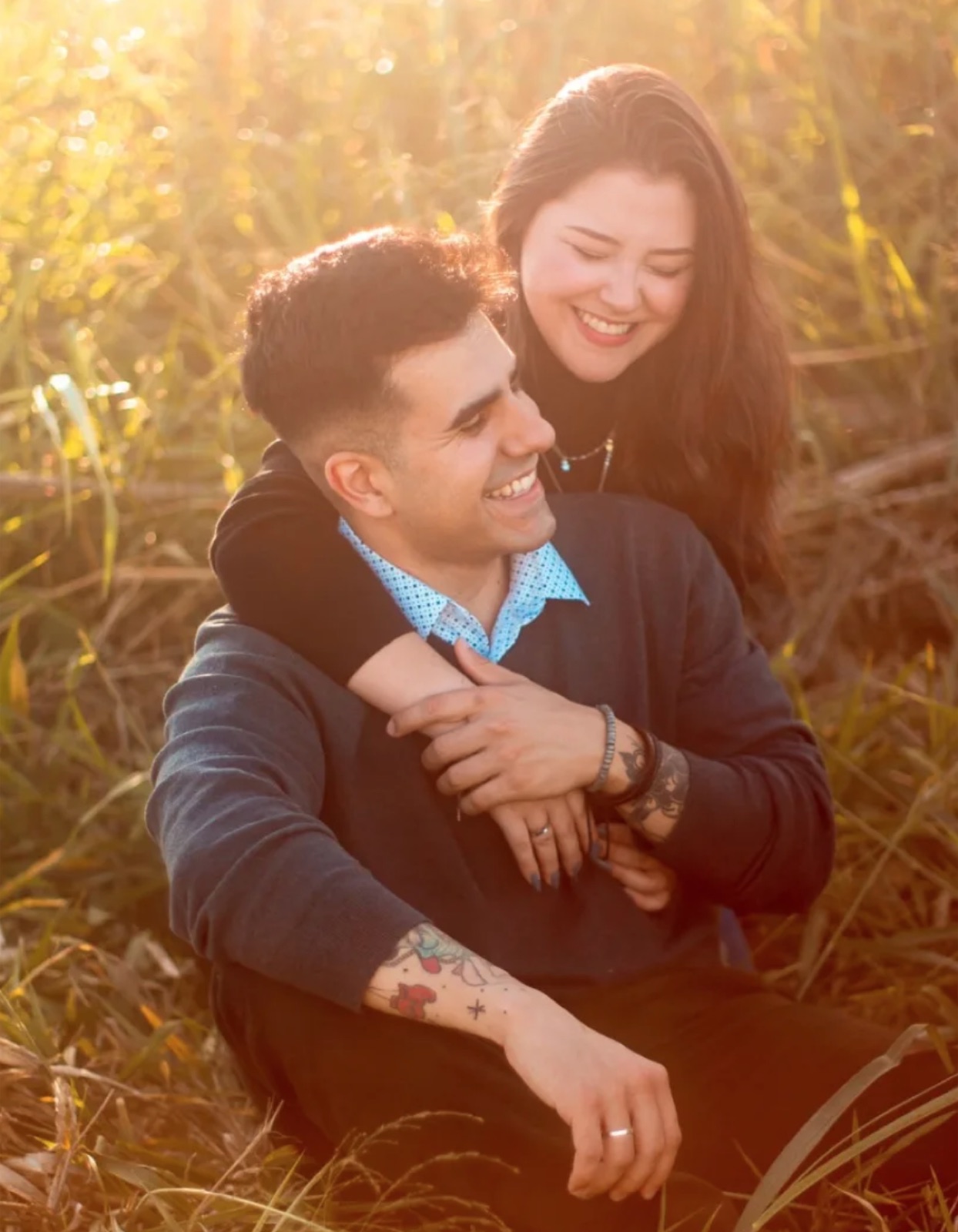 Casal sorrindo abraçado sob luz dourada