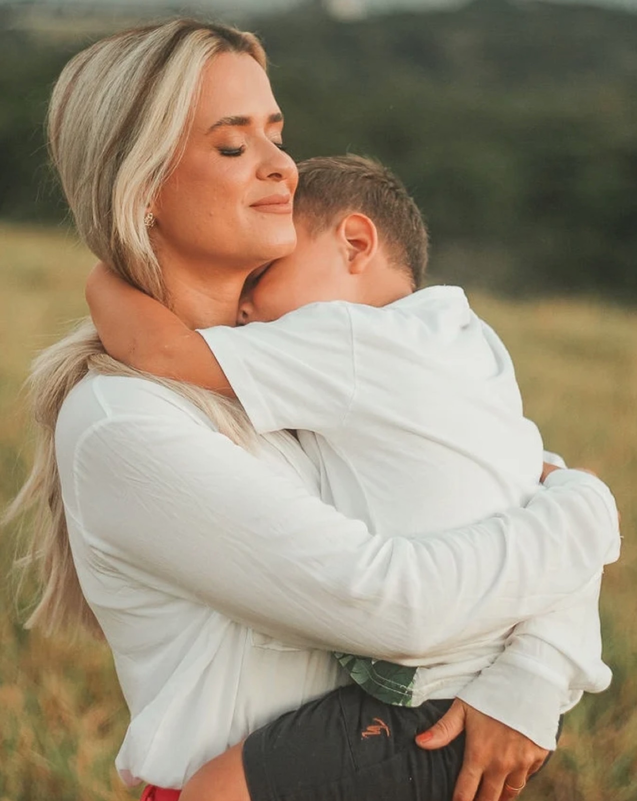Mãe abraçando o filho em campo aberto